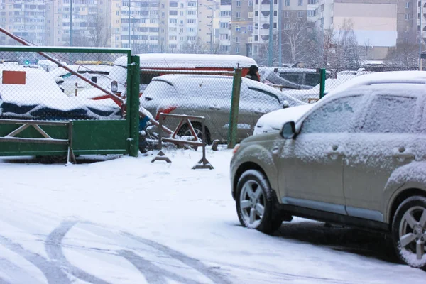 Entering an enclosed private parking lot among the high-rise buildings, no entry sign and a barrier. Many different parked cars covered in snow on a winter day — Stock Photo, Image