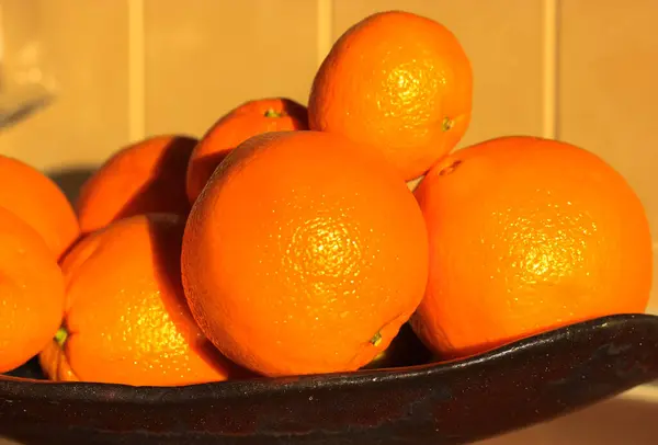 Laranjas maduras perto de um prato preto, frutas sazonais e vitaminas no inverno, boa nutrição — Fotografia de Stock