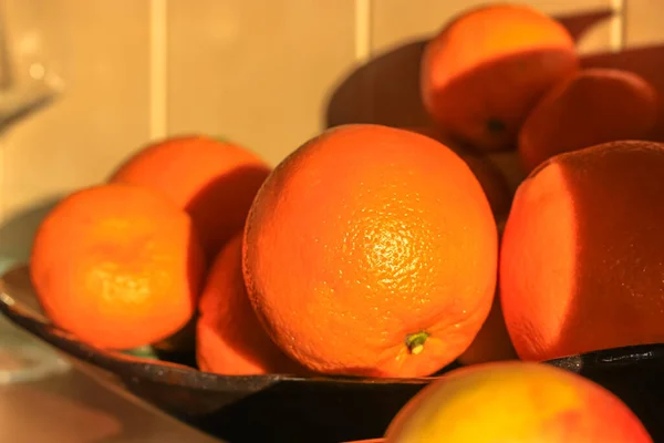 Zralé pomeranče zblízka na černé míse, sezónní ovoce a vitamíny v zimě, dobrá výživa — Stock fotografie