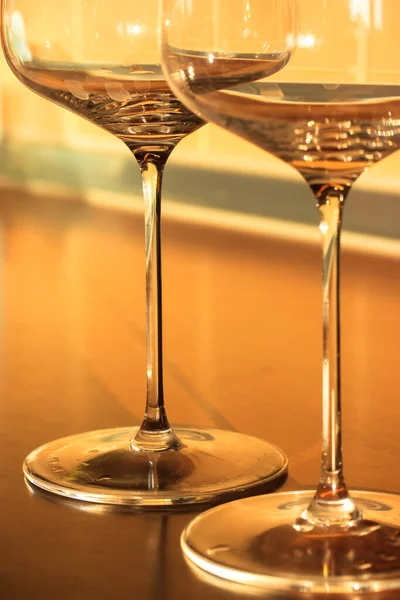 Üres borospoharak vékony lábakon a belső térben, az alkoholos ital tartálya. Sárga háttér. — Stock Fotó