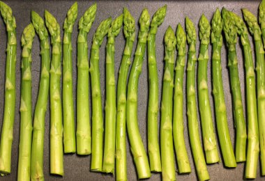 Siyah arka planda bir sürü taze kuşkonmaz, evde pişirilmiş sağlıklı organik yiyecekler..