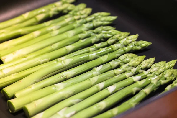 A bunch of ripe fresh asparagus on a black background, healthy organic food — Stock Photo, Image