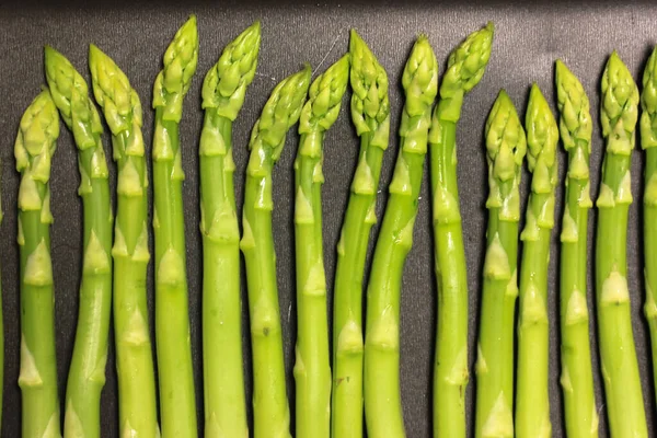 A bunch of ripe fresh asparagus on a black background, healthy organic food — Stock Photo, Image