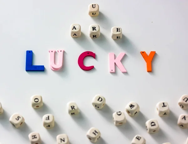 You are lucky colorful words written on wood blocks, white table background and abc alphabet, black and white letters on wooden blocks. Business success and motivation for action — Stock Photo, Image