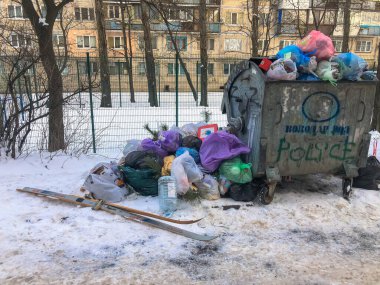 Kışın çöp tenekesinin yanında bir sürü çöp, kırık kayaklar ve plastik torbalar.