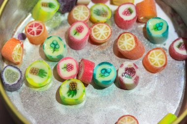 İçinde farklı tatlar olan çok renkli lolipopları olan yarısı boş teneke kutu.