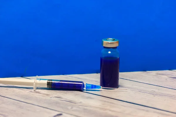 Stole Modrém Pozadí Stěny Stojí Průhledná Ampulka Skla Izolovaná Vakcína — Stock fotografie