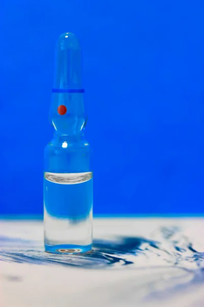Jedna Průhledná Skleněná Ampulka Stojí Stole Modré Pozadí Izolovaná Vakcína — Stock fotografie