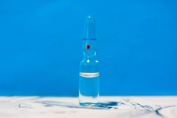 Ett Glas Medicinsk Transparent Ampull Står Ett Bord Blå Bakgrund — Stockfoto