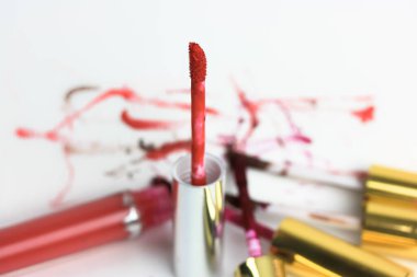 Beyaz bir masadaki tüpte sıvı kırmızı dudak parlatıcısı, bir sürü parlatıcı, bulanık arkaplan. Kızlar için dekoratif kozmetik. Yüksek kalite fotoğraf