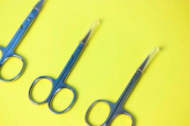 Keskin çelik manikür makası seti sarı yeşil masa yüzeyinde izole bir şekilde yatmaktadır. Çapraz dağılmış makas. Manikür ve pedikür için profesyonel aletler. Güzellik dürbünü. Üst Manzara. Düzgünce.