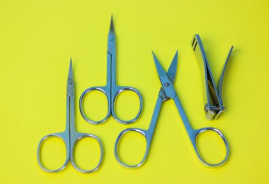 Sarı yeşil masa yüzeyinde izole edilmiş keskin çelik manikür makas ve çiviler. Manikür ve pedikür için profesyonel aletler. Güzellik dürbünü. Masadaki makası aç. Üst Manzara. Düzgünce.