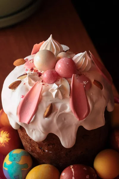 Traditional easter festive cake with frosting close-up. Multicolored Easter eggs in the foreground. High quality photo.