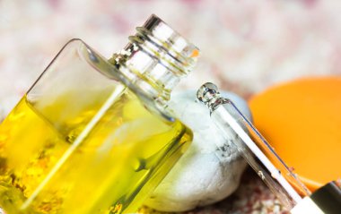 Pipette altın sarısı yağ serumu. Yüz derisi ve cilt yenilenmesi için doğal organik kozmetik ürünler. Şeffaf cam şişe ve sıvı cilt bakımı güneş kremi yağı. Deniz teması, çakıl taşları, kum. 