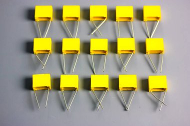 Sarı film kondansatörleri gri arka planda. Elektronik radyo bileşenleri.