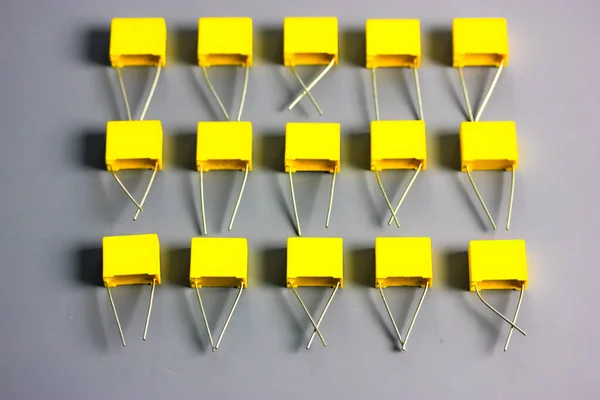 Condensadores de película amarilla sobre fondo gris vista superior. Componentes electrónicos de radio. — Foto de Stock