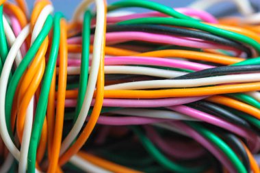 Bir sürü renkli elektrik, araba, bilgisayar ve telefon kablosu birbirine dolanmış. Turuncu, yeşil, pembe, gri arka planda beyaz kablolar. Bilgisayar ağları, elektrikçi hizmetleri kavramı.
