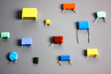 Gri arkaplandaki alt minyatür polipropilen çok renkli film kondansatörleri. Antika elektronik parçalar. Farklı boyut ve renkte rezistans ve kapasitörler. HiFi Ses Parçaları. Radyo bileşenleri. 