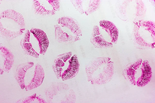 Abstract pink kisses isolated on white background. Lots of female lip prints on paper. Beautiful lips stamps isolated. Valentine\'s day, romantic mood and love concept. Lipstick kisses. Print of lips.