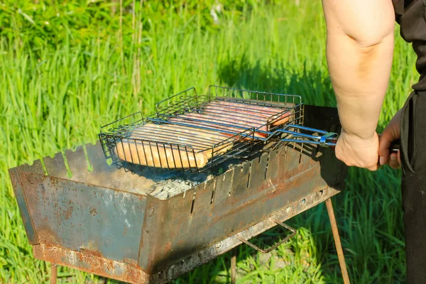 非スティックグリルグリッド上の生ソーセージは 古い金属製のバーベキュー 屋外で肉を準備する 晴れた夏の日に森の中でピクニック 緑の草の背景 健康食品を屋外で調理するプロセス — ストック写真