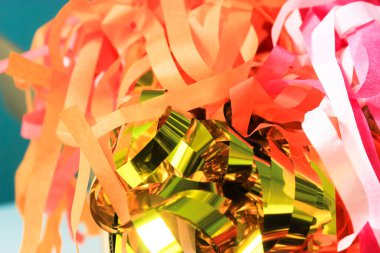 Çok renkli püsküllü püskül süsleri. Şenlik arka planı. Kutlama, karışık altın, sarı, pembe kağıt bantlar. Moda bir tatil dekoru. Etkinlik, yıldönümü, doğum günü partisi için tebrik ederim. Eğlenceli konsept. 