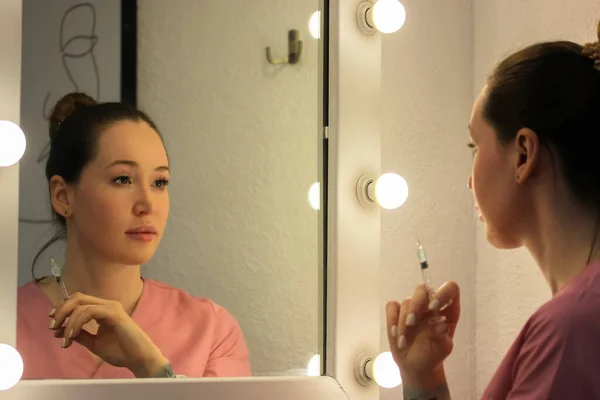Een Cosmetoloog Een Roze Medische Jurk Staat Voor Een Spiegel — Stockfoto