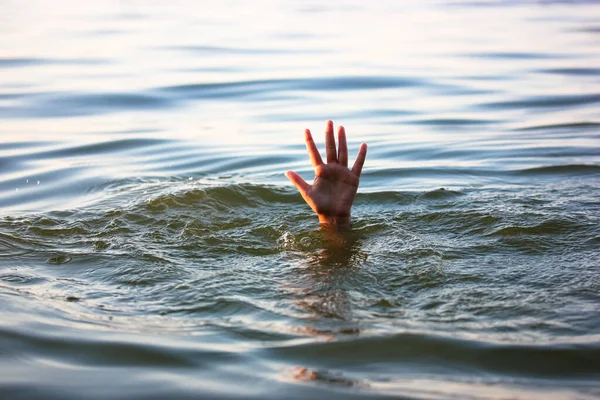 A man is drowning in water. A hand peeks out from under a water. A drowning person needs help, rescue. A risk, danger for living in the sea, river, ocean, pond. Death, SOS concept. Drowning victim