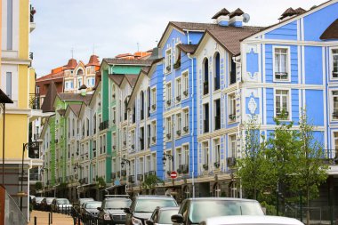 Çok renkli eski modern evlerin cephesi. Bakış açısıyla Avrupa 'nın rahat caddesi. Yaz günü yol kenarında park etmiş arabaların olduğu bir şehir caddesi. Modern renkli mimari. Ön cephe oluşturuluyor