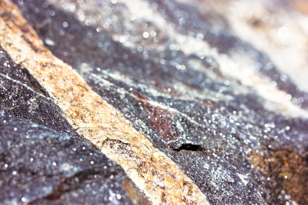 石のテクスチャを近いうちに花崗岩 侵入岩の背景 ゴールデンまたはベージュのストライプと大規模な未処理の濃い灰色の輝く石の表面 天然素材 大理石岩のマクロ写真の背景 — ストック写真