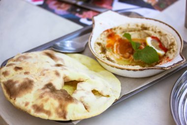 Aperatif klasik humus zeytinyağı, paprika, limon, baharat, yeşil nane yaprağı ve beyaz seramik kasede. Metal tepside Pita ekmeği. Nohut, vejetaryen, vejetaryen yemeği. Arap yemekleri, lezzetli çerez üst görünümü.
