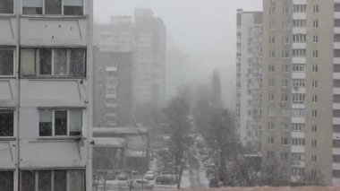 Düz balkondan çok katlı panellere, binalara, evlere, pencerelere ve soğuk bir kış gününde soğuk bir caddeye bakan sokağa bakın. Kar yağışı, kar taneleri yavaşça düşüyor.