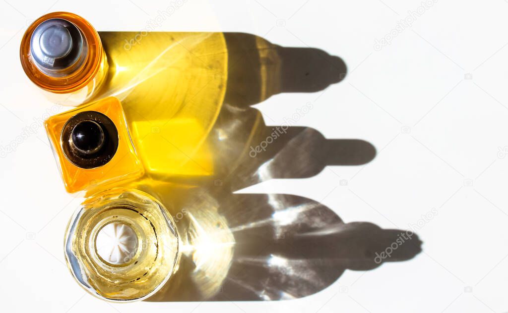 Yellow cosmetic bottles with essential oil on white table top view. Contrasting shadows. Spa treatment, wellness, body, face care. Beautiful minimalistic composition flatly. Beauty products copy space