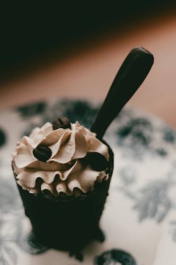 Delicious coffee dessert with whipped cream and coffee beans, close-up vertical shot. This decadent dessert features a rich coffee flavor and is perfect for any coffee lover. Dark chocolate with cream