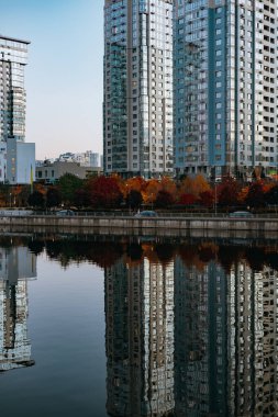 Kyiv, Ukrayna 4 Ekim 2025 Modern rıhtım binaları alacakaranlıkta sakin suya yansıdı. Evlerin simetrik yansımaları, suyun yüzeyine çarpıcı bir görsel efekt modern mimari