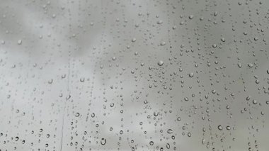 Bulutlu bir gökyüzüne düşen yağmur damlaları güzel, doğal bir desen oluşturur. Su damlacıkları pencere üzerinde çarpıcı, soyut bir etki yaratıyor. Yumuşak, dağınık bir arka plan..