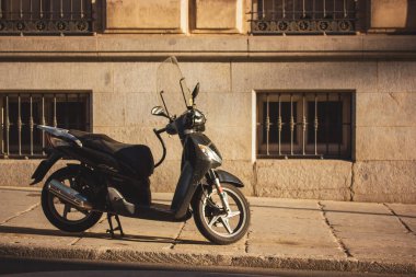 Madrid, İspanya 1 Haziran 2024 siyah bir scooter bir binanın önündeki kaldırıma park etmiş. Parmaklıklı pencereleri olan eski bir binanın arka planına bakan şık bir scooter yan görüntüde yakalanır..
