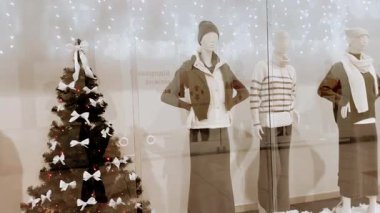 KYIV, Ukrayna 6 Aralık 2025 Noel vitrininde kış modası giyen mankenler. Festivalin vitrininde kadın kıyafetleri giymiş mankenler ve süslü bir Noel ağacı yer alıyor..