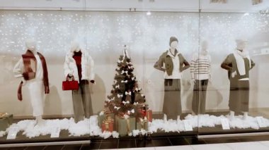 KYIV, Ukrayna 6 Aralık 2025 Noel vitrininde kış modası giyen mankenler. Festivalin vitrininde kadın kıyafetleri giymiş mankenler ve süslü bir Noel ağacı yer alıyor..
