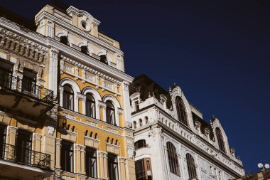 Kyiv, Ukrayna 13 Aralık 2025 Klasik Avrupa mimarisi, klasik sarı ve beyaz bina cepheleriyle süslenmiş sıva ayrıntıları ve parlak güneşli güneş temalı işlenmiş demir balkonlar
