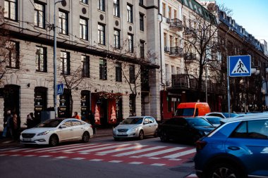 KYIV, Ukrayna 13 Aralık 2025 Şehir Caddesi. Avrupa 'da günlük hayatı ve trafiği sembolize eden klasik bina cepheleri ve mavi gökyüzü ile kırmızı ve beyaz yaya geçidinde park etmiş ve hareket halindeki arabalar.