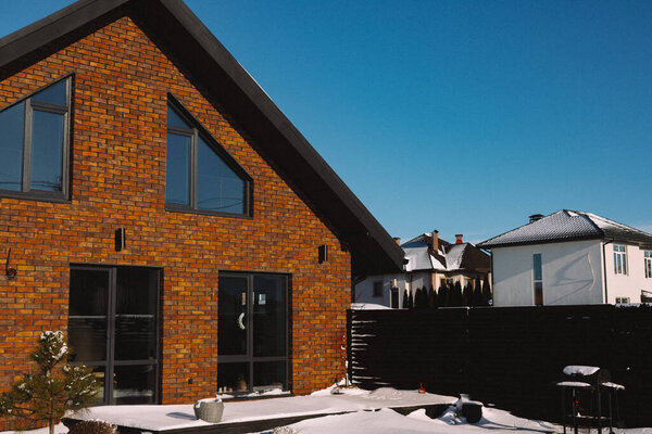 KYIV, Ukraine 1 January 2026 Modern suburban house exterior with a brown or orange brick facade and large windows in winter day. Contemporary residential architecture with a pitched roof. Real estate