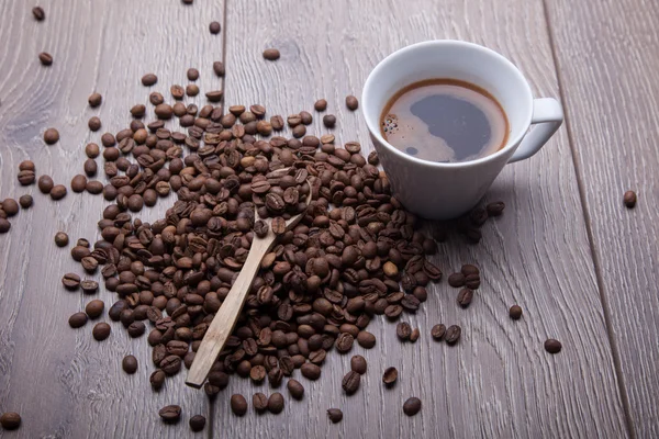 Tahta arka planda beyaz bir fincan kahve.