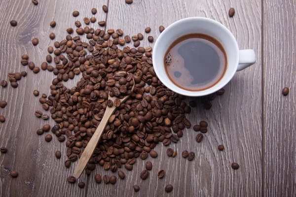 Tahta arka planda beyaz bir fincan kahve.