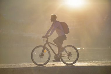 Bisikletli bir adam açık deniz kenarında bisiklet sürüyor.