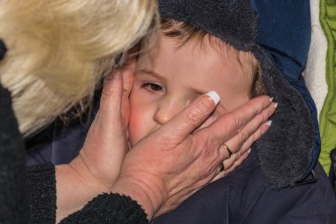 Kadın losyon yüzünde küçük bir çocuk koyuyor. 