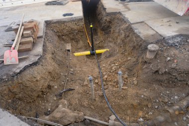 Mühendislik ve ısıtma sistemlerinin kurulumu üzerinde çalış. İki plastik boru, biri gaz borusu için sarı diğeri de elektrik hattı için siyah. Kum çukurundalar..