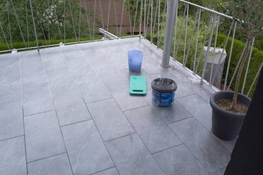 Tiler laying  tiles on the floor of a balcony and grouted. clipart