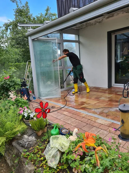 Mann Reinigt Wintergarten Mit Hochdruckreiniger Hochdruckreiniger Auf Terrassenglasoberfläche — Stockfoto