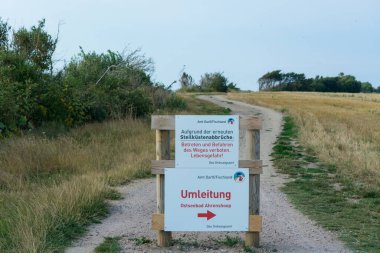 Almanca yazılı beyaz uyarı işareti - Darss 'taki Baltık Denizi' ndeki kayalıklardan sakının