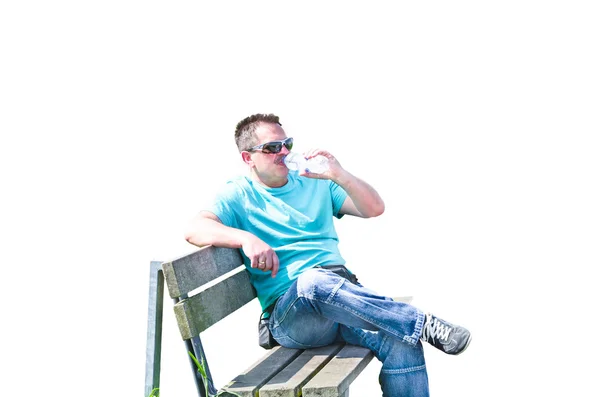 Człowiek na ławce w picie wody mineralnej. — Zdjęcie stockowe